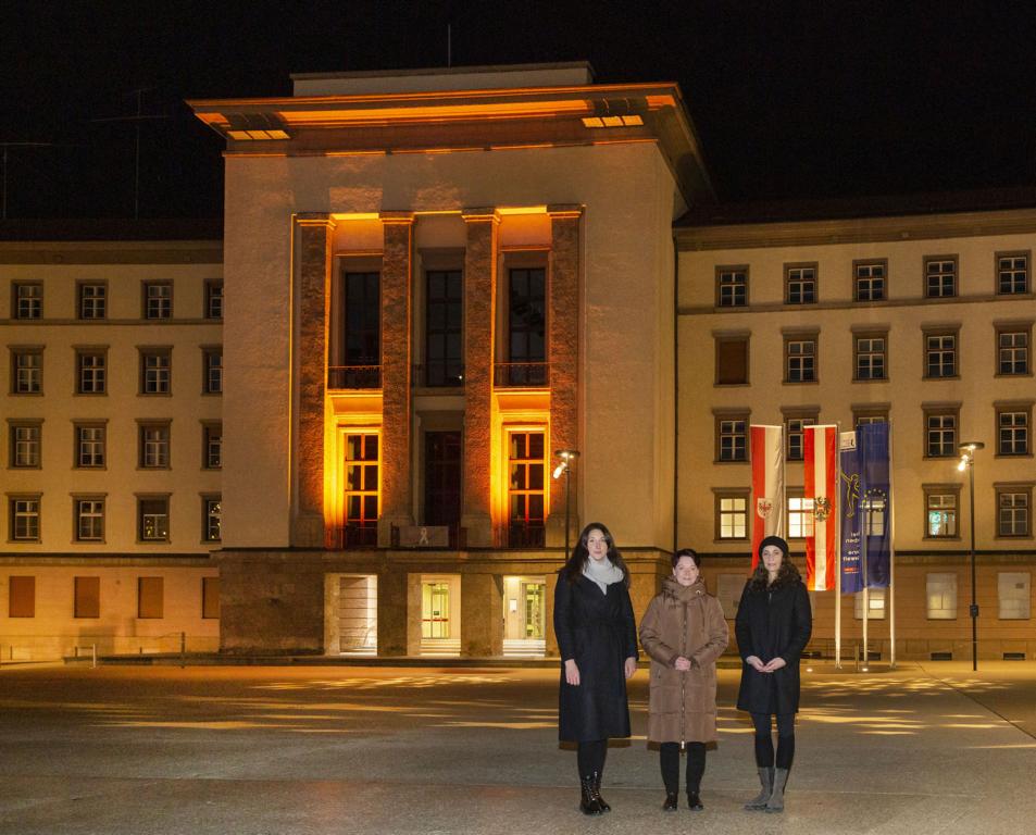 LTPin Sonja Ledl-Rossmann (Mitte), VPin Sophia Kircher (li.) und LRin Eva Pawlata vor dem orange beleuchteten Landhaus, Foto: Tiroler Landtag/Die Fotografen