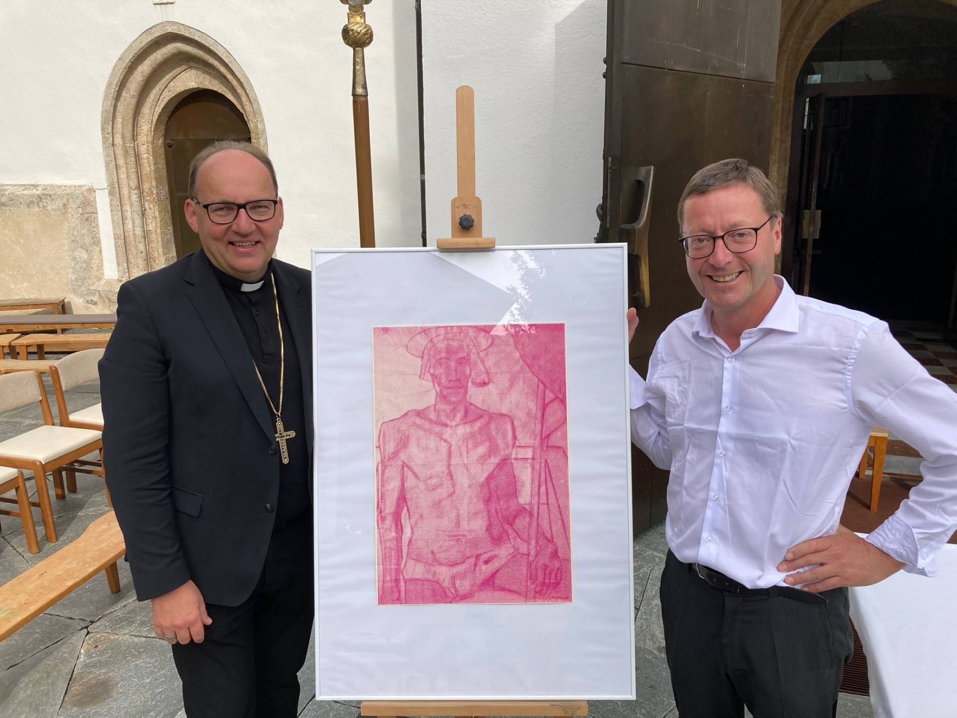 Bischof Hermann Glettler &uuml;berreichte Dekan Franz Troyer einen Kunstdruck des "Auferstandenen" von Albin Egger-Lienz, nachempfunden vom K&uuml;nstlerkollektiv SUSI POP. Das Original ist Teil der Sonderausstellung "Nic&auml;a-Blicke nach Innen" in Schloss Bruck und h&auml;ngt in der Pfarrkirche St. Andr&auml;. Foto: Stangl