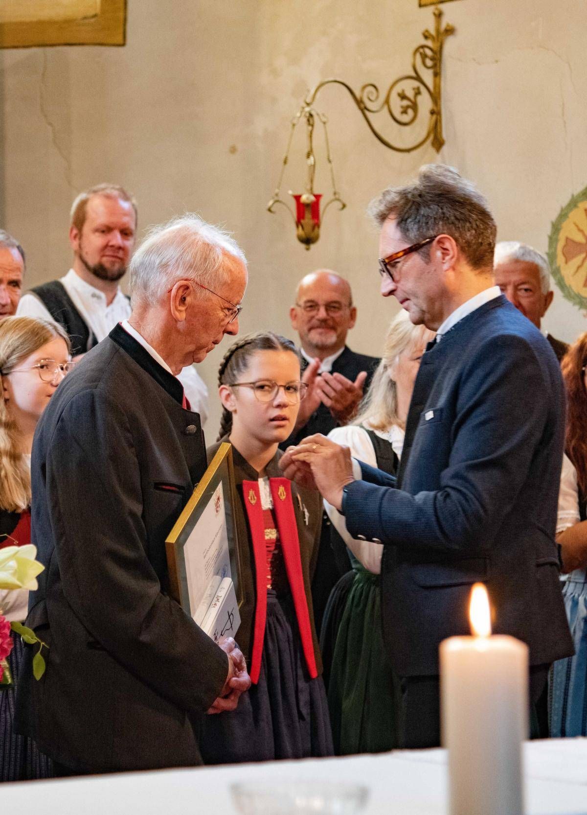 Martin Waldauf (r.) steckt Bartholom&auml;us Klaunzer die Ehrenzeichen des Chorverbandes Tirol und &Ouml;sterreich an.
