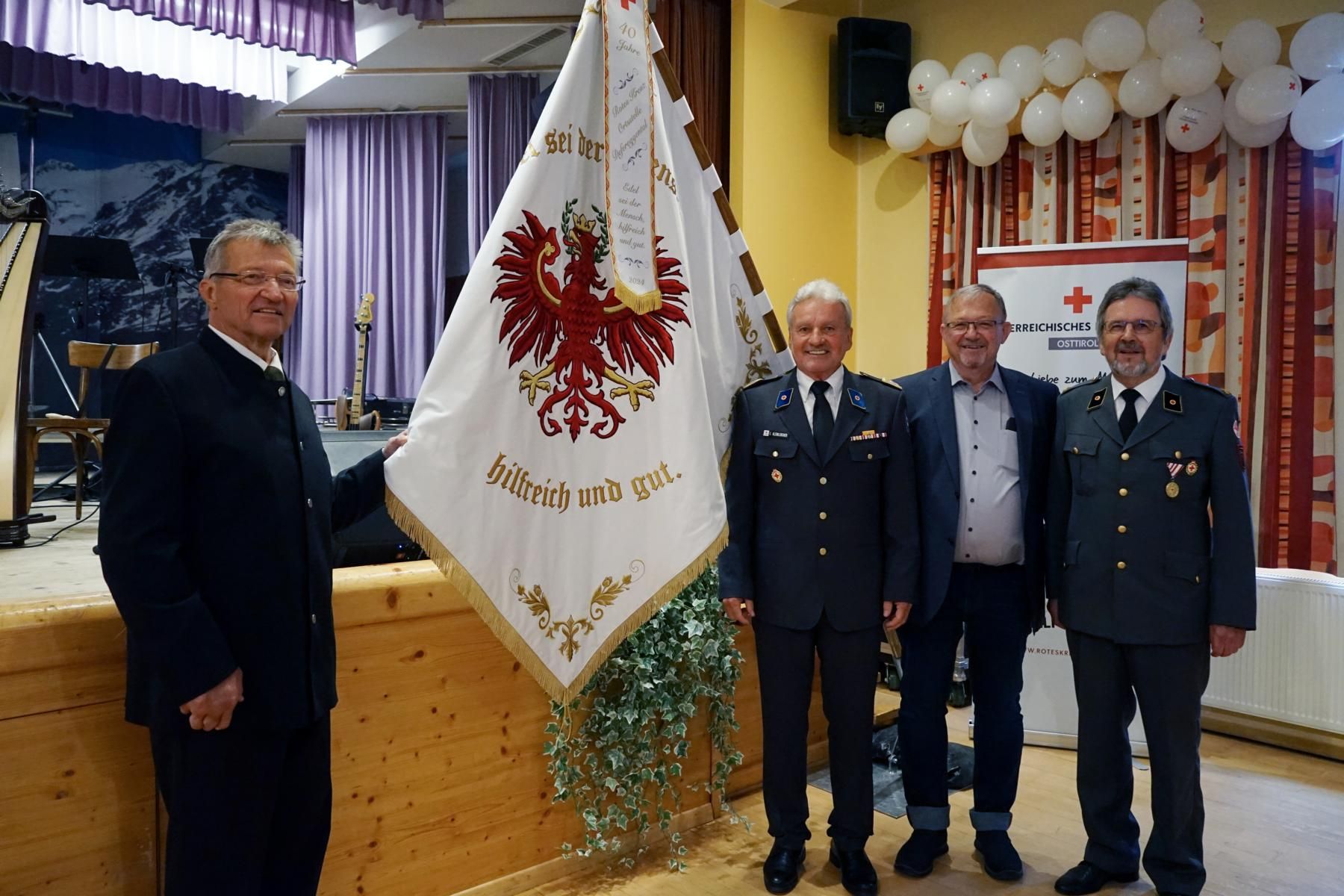 Die neue Vereinsfahne mit den Unterst&uuml;tzern. v.l. Dr. Winfried Kuenz, Vizepr&auml;sident &Ouml;RK LV Tirol und Bezirksstellenleiter&ndash; Egon Kleinlercher, Dr. Gerald Kuenz, Rot-Kreuz-Arzt Dr. Ottokar Widemair  Foto: &Ouml;RK Osttirol.